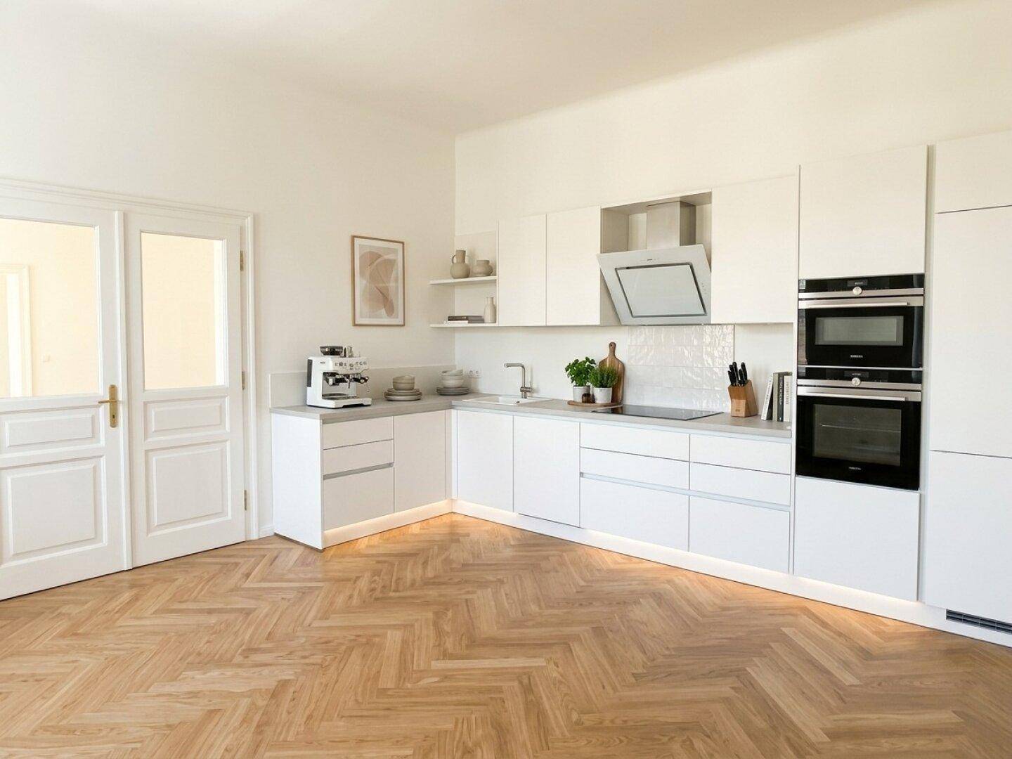 Moderne Einbauküche in Weiß mit integrierten Geräten und Fischgrätparkettboden.