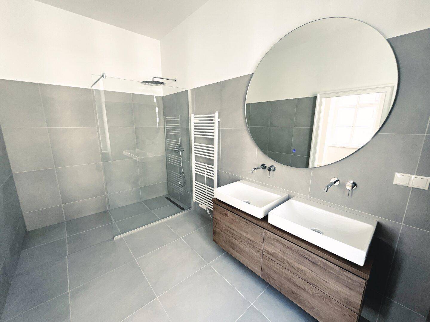 Modernes Badezimmer mit Doppelwaschbecken, begehbarer Dusche und großem Spiegel, sehr funktional.