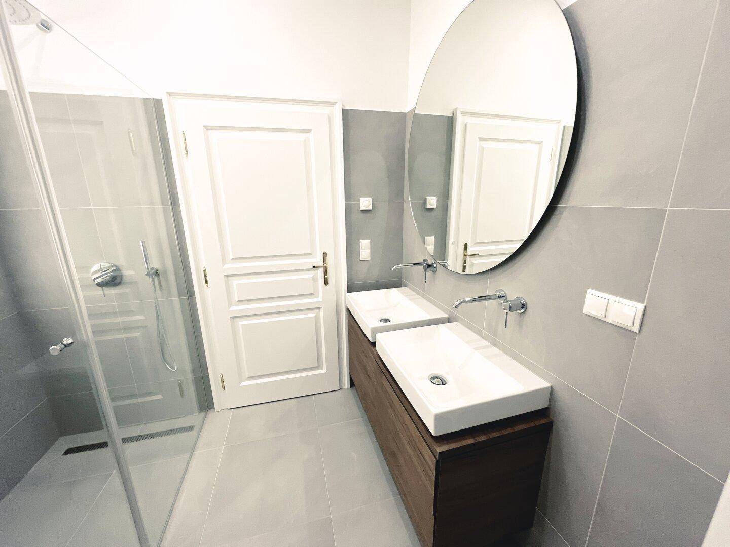 Modernes Badezimmer mit Doppelwaschbecken, begehbarer Dusche und großem Spiegel, sehr funktional.