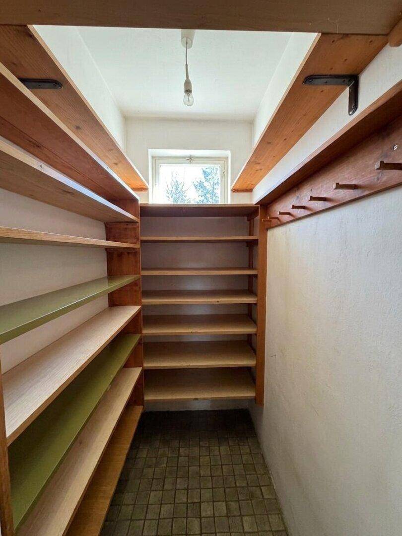 Praktischer Abstellraum mit vielen Holzregalen und einem kleinen Fenster für Tageslicht.