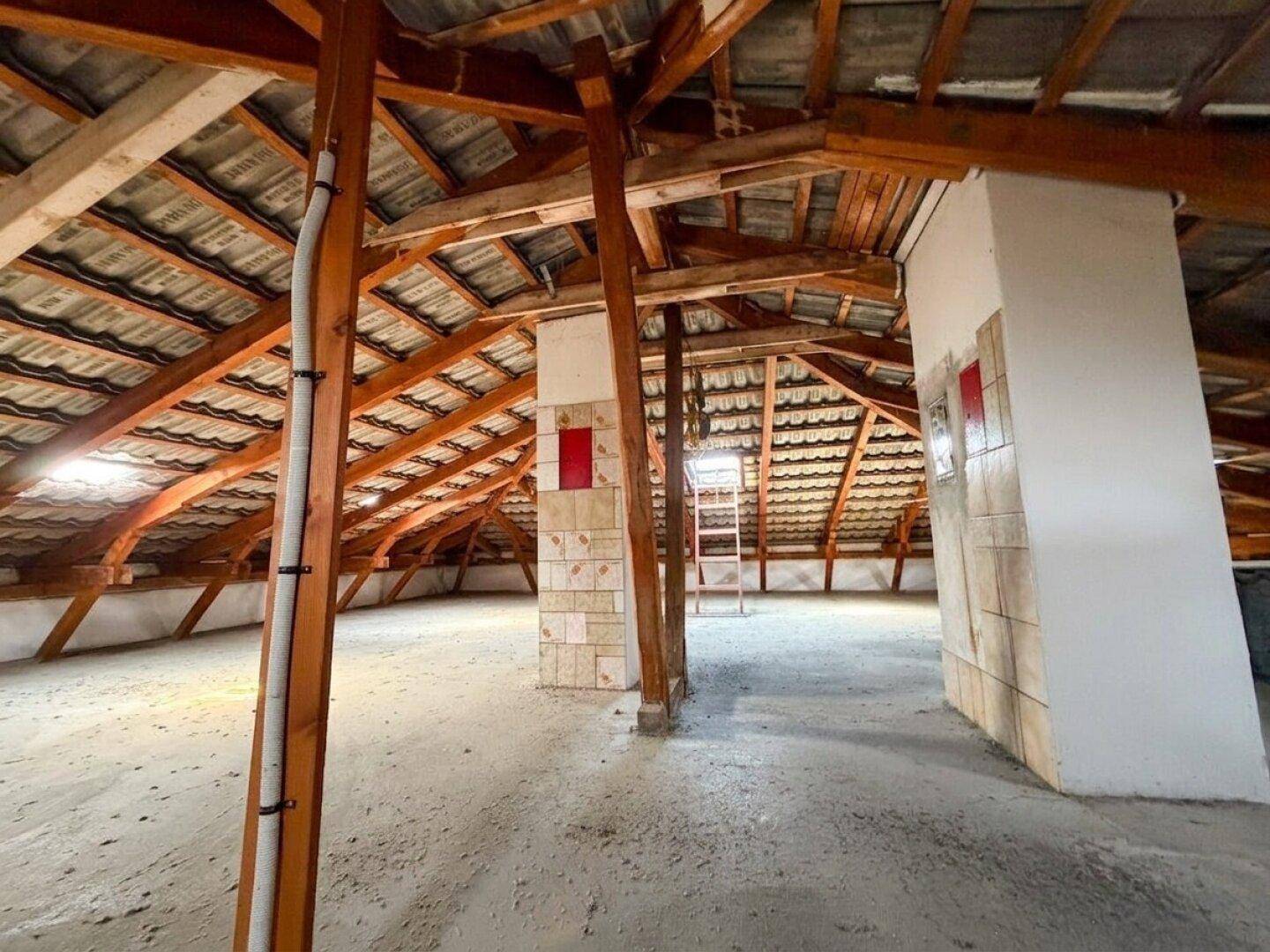Großer Dachboden mit sichtbaren Holzbalken und Dachziegeln, der Ausbaupotenzial bietet.