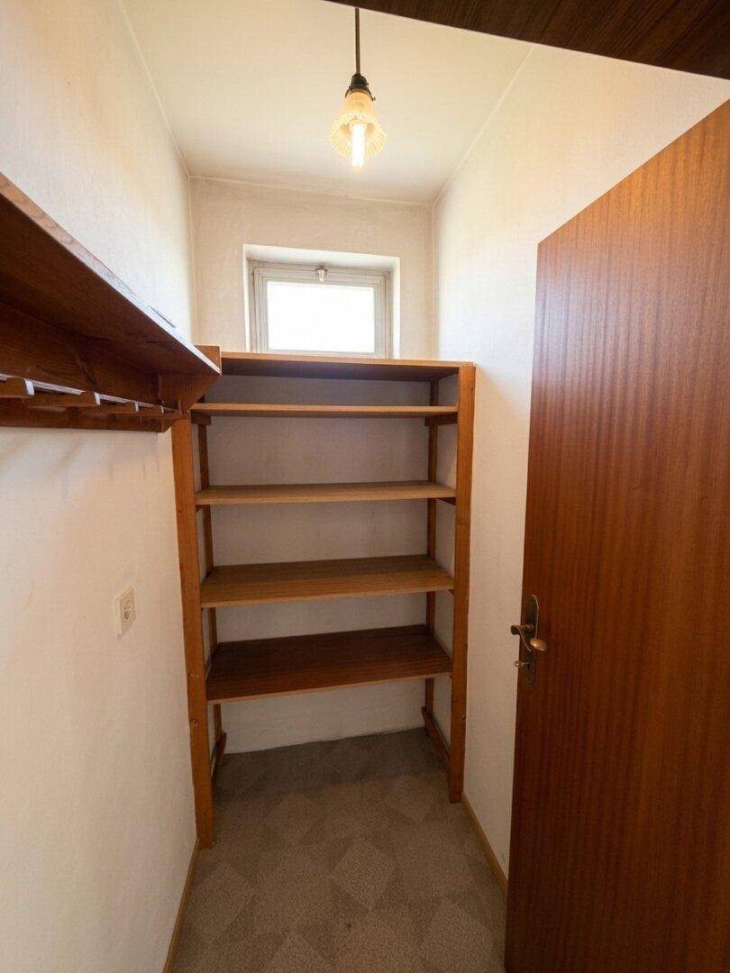 Abstellraum mit Holzregalen und einer Tür, ideal für zusätzlichen Stauraum.