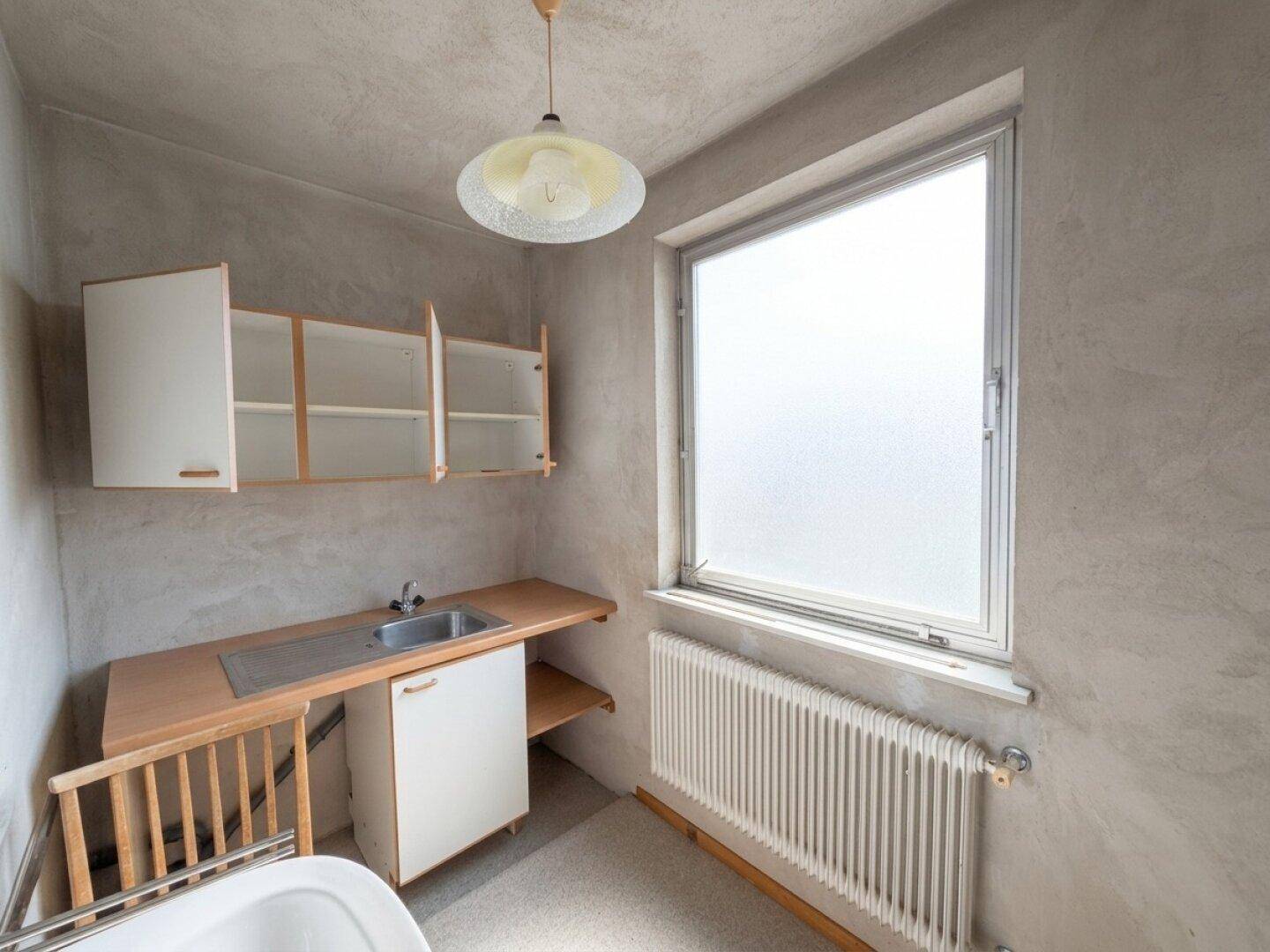 Hauswirtschaftsraum mit Waschbecken, Arbeitsplatte und Fenster, bereit zur Nutzung.