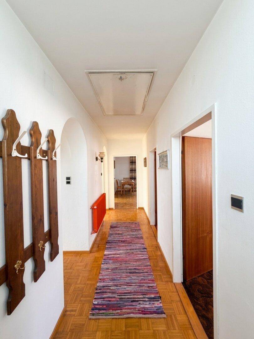 Langer Flur mit Parkettboden, Garderobe und Blick in den hinteren Bereich.