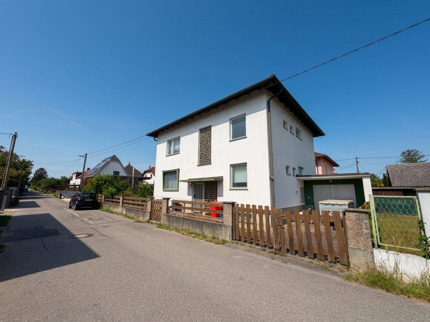 Ansicht des Einfamilienhauses von der Straße mit angrenzender Garage und gepflegtem Vorgarten.