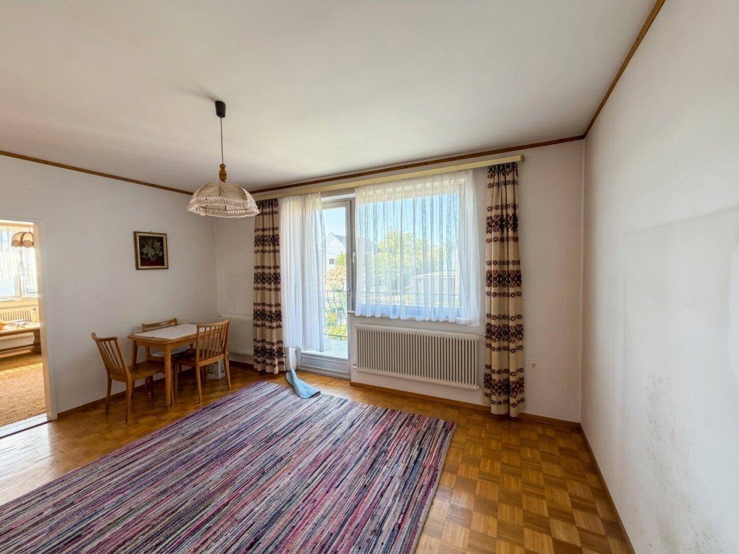 Esszimmer mit Parkettboden, Teppich und Zugang zu einem Balkon oder einer Terrasse.