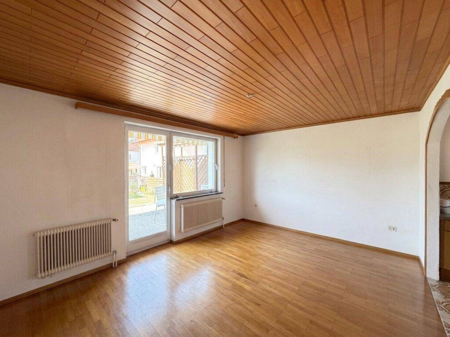 Helles Wohnzimmer mit Parkettboden, Holzdecke und Zugang zur Terrasse oder zum Garten.