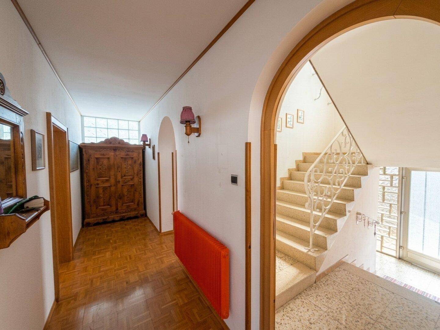 Flur mit Parkettboden, Holzschrank und Zugang zum Treppenhaus.