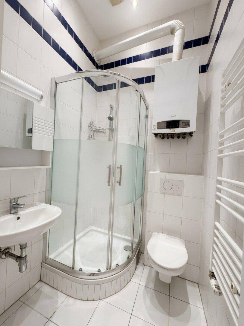 Modernes Badezimmer mit Duschkabine, WC und Waschbecken in weiß-blauer Fliesengestaltung.