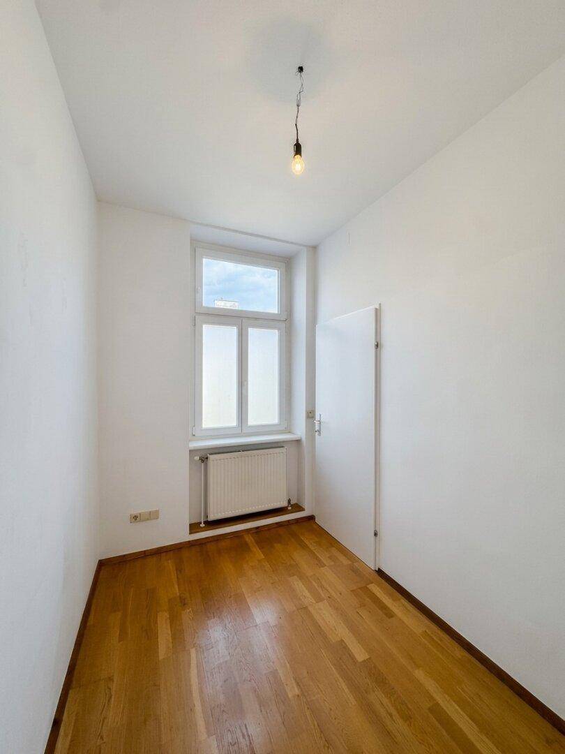 Kleines, helles Zimmer mit Parkettboden und Fenster, ideal als Kinder- oder Arbeitszimmer.