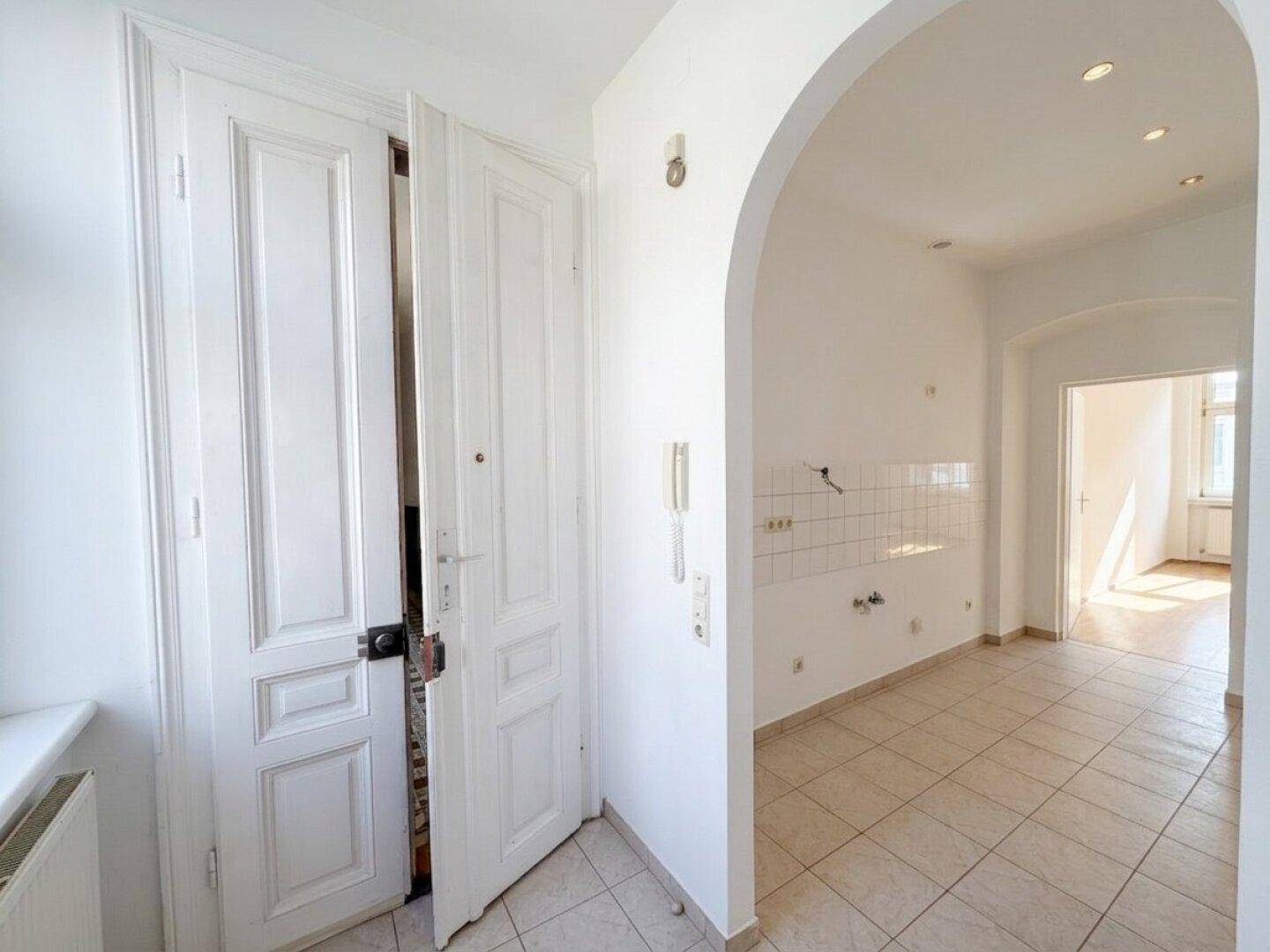 Eingangsbereich mit Doppeltür und Fliesenboden, führt in den Küchenbereich der Wohnung.