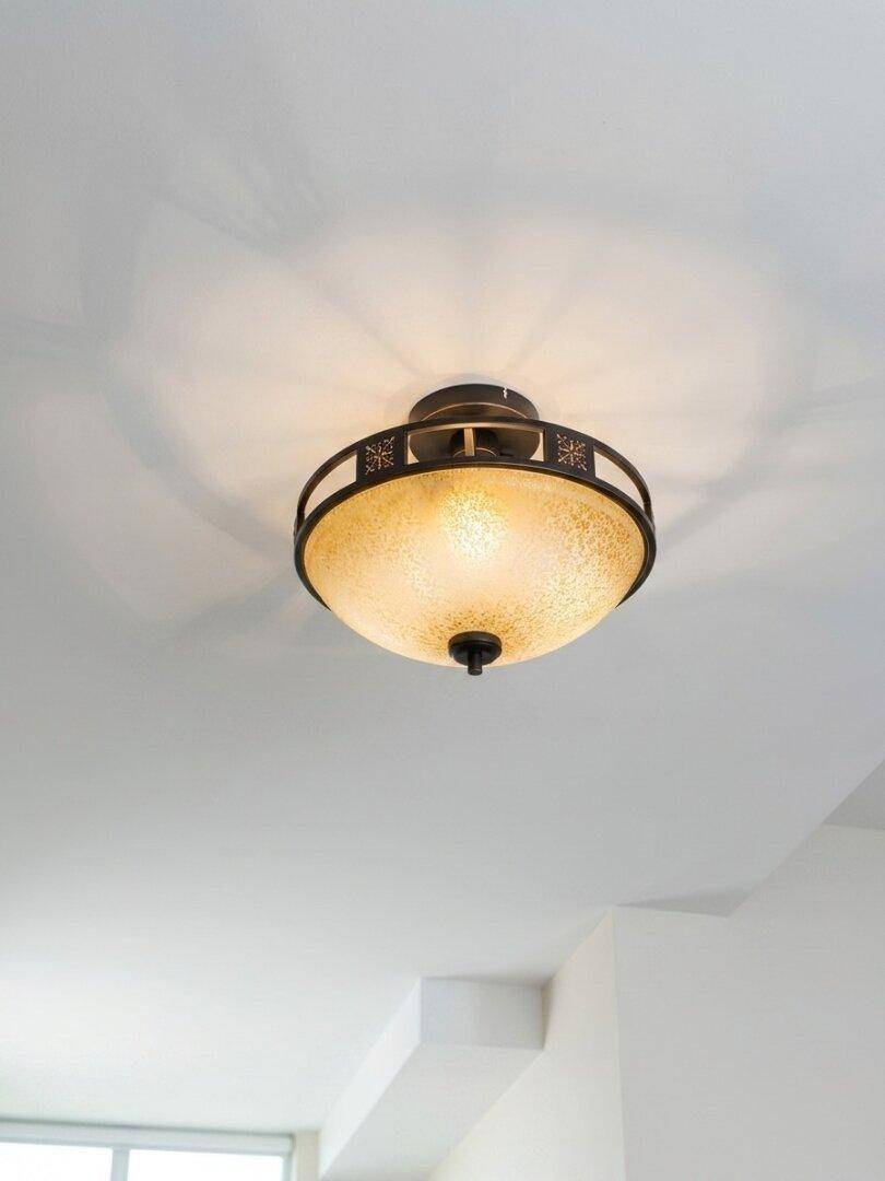 Deckenleuchte mit strukturiertem Glasschirm und dekorativem Metallrahmen an einer weißen Decke.
