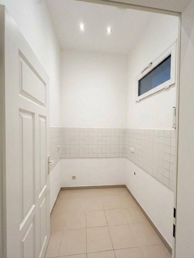 Kleiner, gefliester Raum mit Fenster, ideal als Abstellraum oder für eine Küchenzeile.