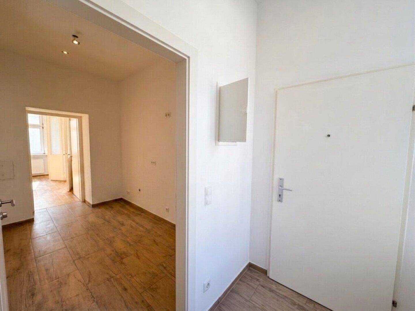 Heller Eingangsbereich mit Holzoptik-Fliesenboden und Zugang zu weiteren Räumen der Wohnung.