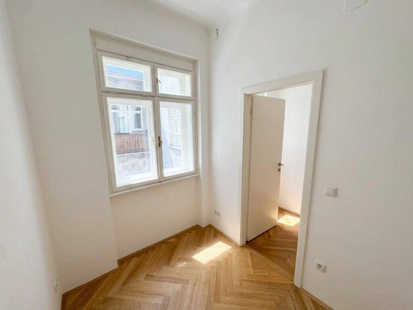 Gemütliches Zimmer mit Fischgrätparkett und Fenster, ideal als Kinder- oder Arbeitszimmer.