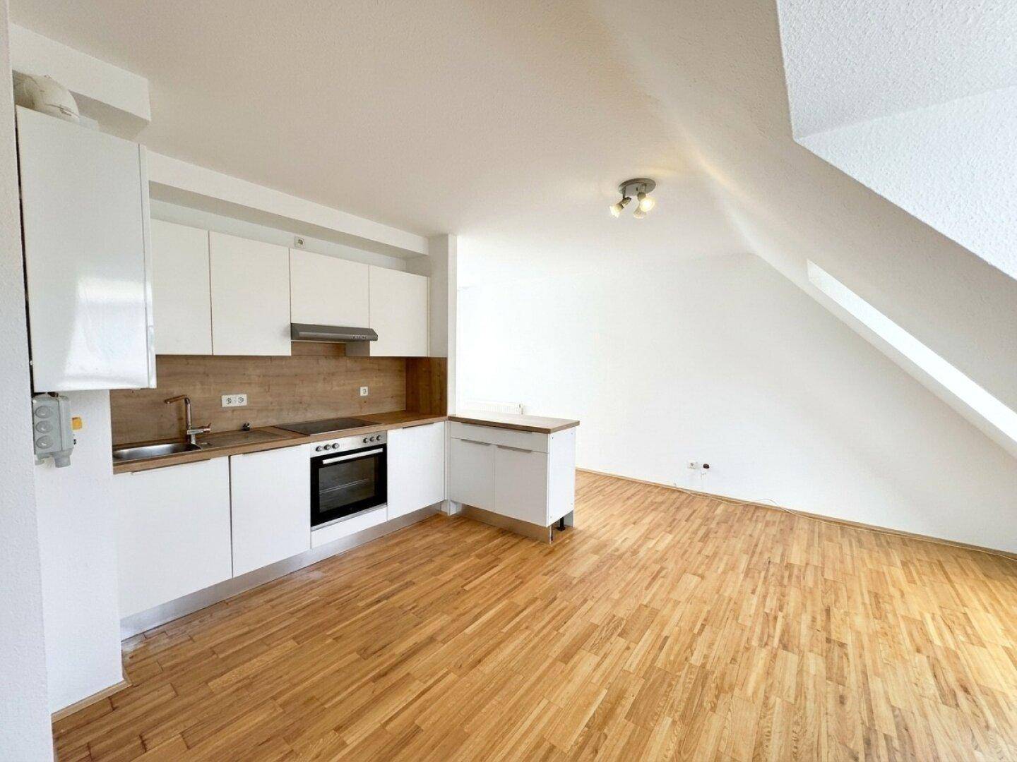 Funktionale Küchenzeile in heller Dachgeschosswohnung mit Holzboden und viel Tageslicht.