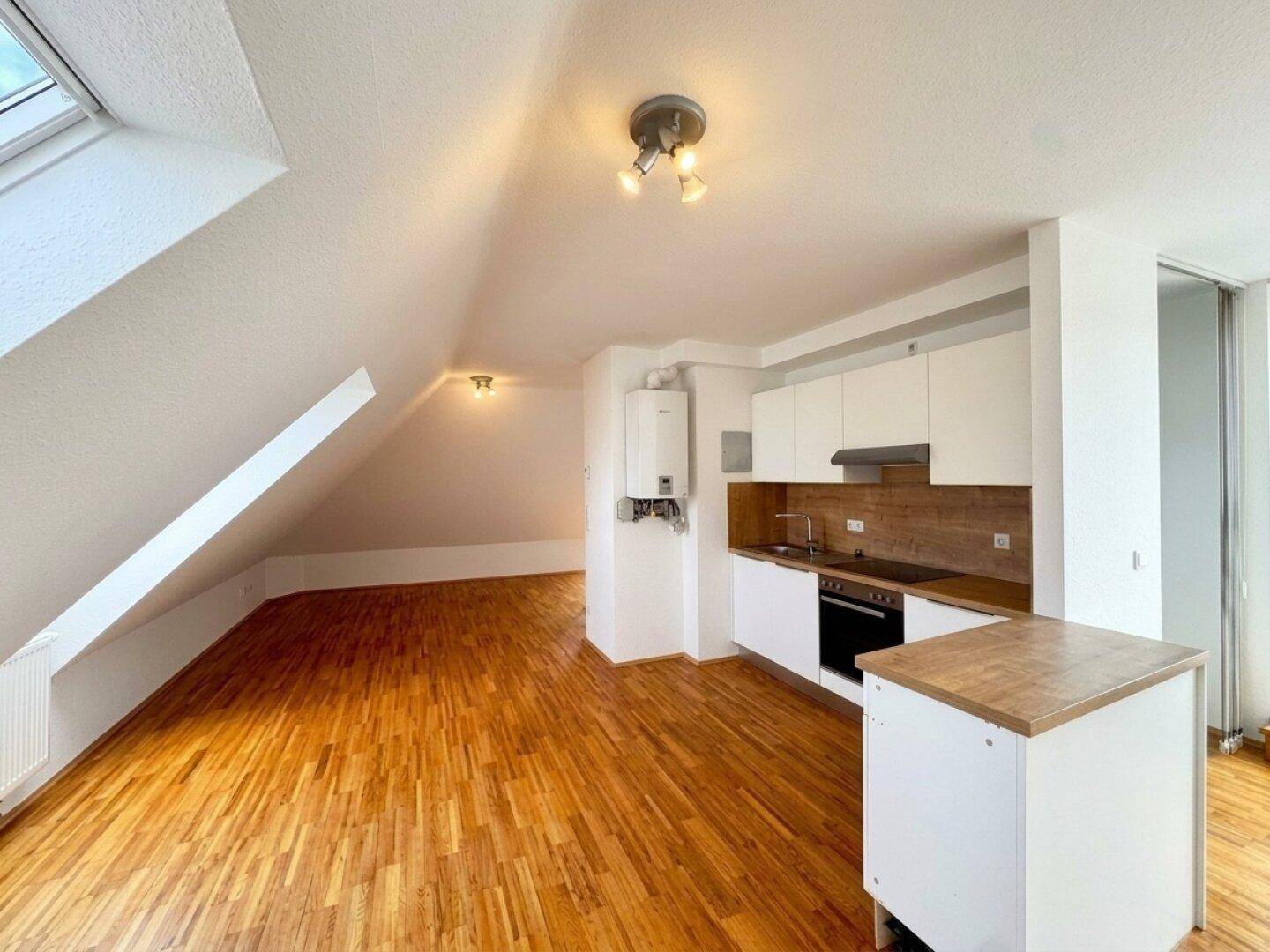 Helle Dachgeschosswohnung mit integrierter Küchenzeile, Holzboden und Dachfenstern.