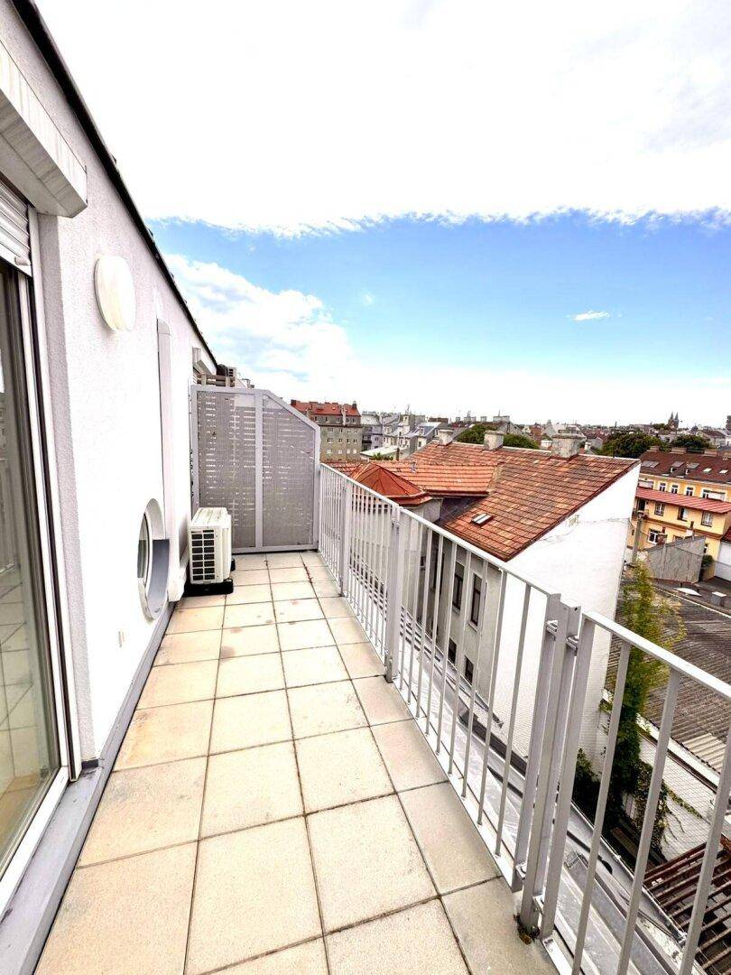 Langer Balkon mit Fliesenboden und weitem Blick über die Dächer der Stadt.