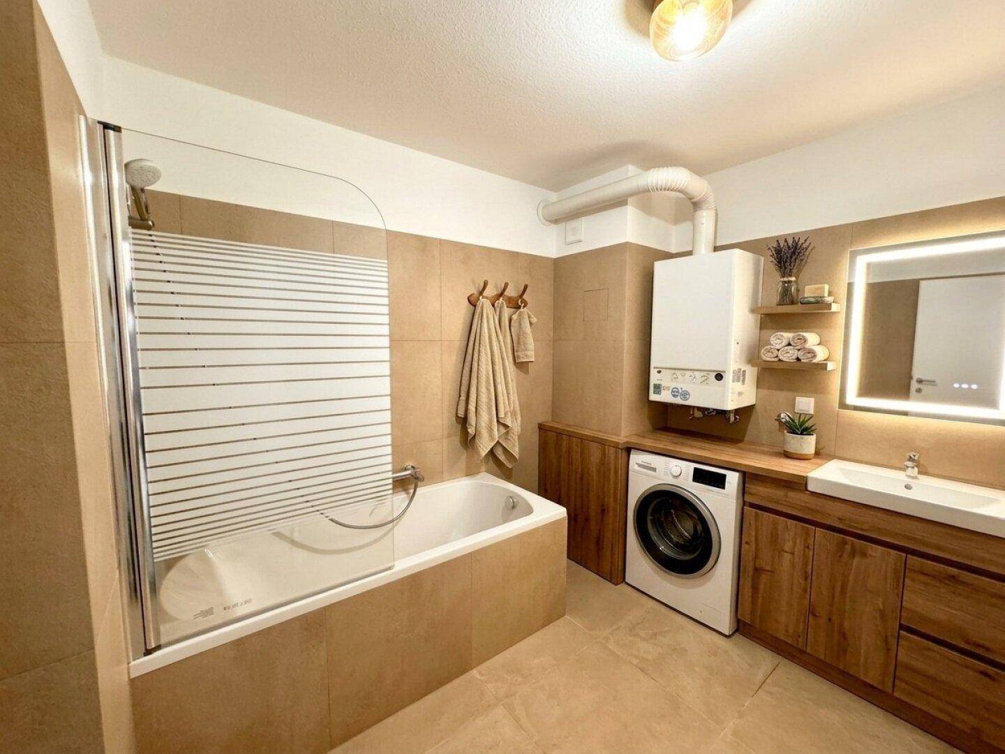 Funktionales Badezimmer mit Badewanne, Dusche und Holzunterschrank, ausgestattet mit Waschmaschine.