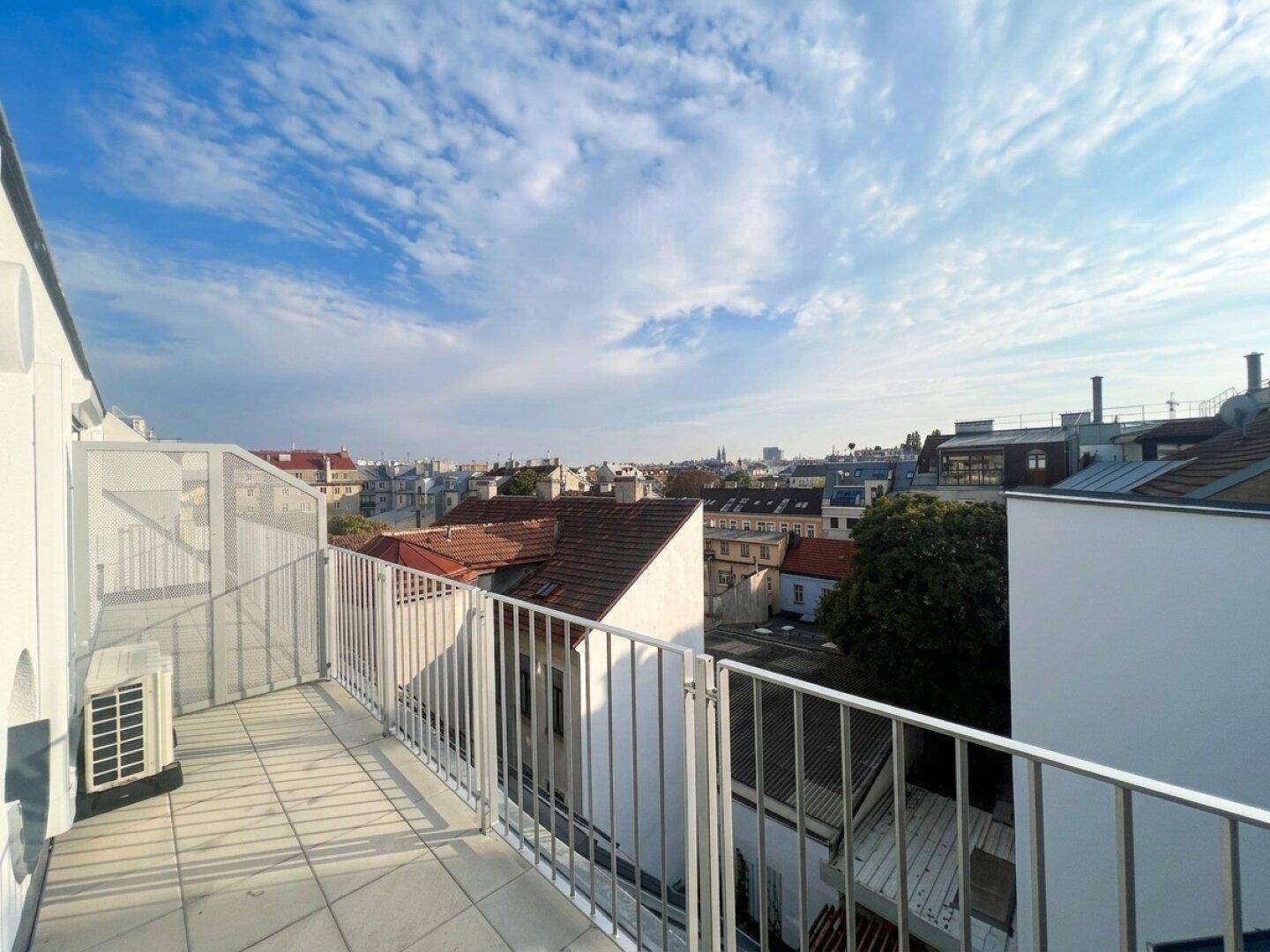 Geräumiger Balkon mit Stadtblick und blauem Himmel, bietet Platz für Entspannung.