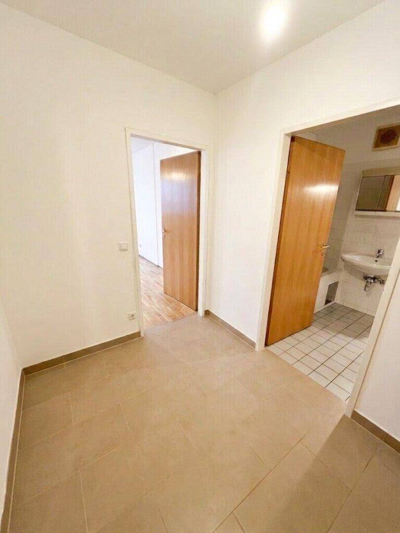 Flur mit Fliesenboden, der zu verschiedenen Zimmern und einem Badezimmer führt.