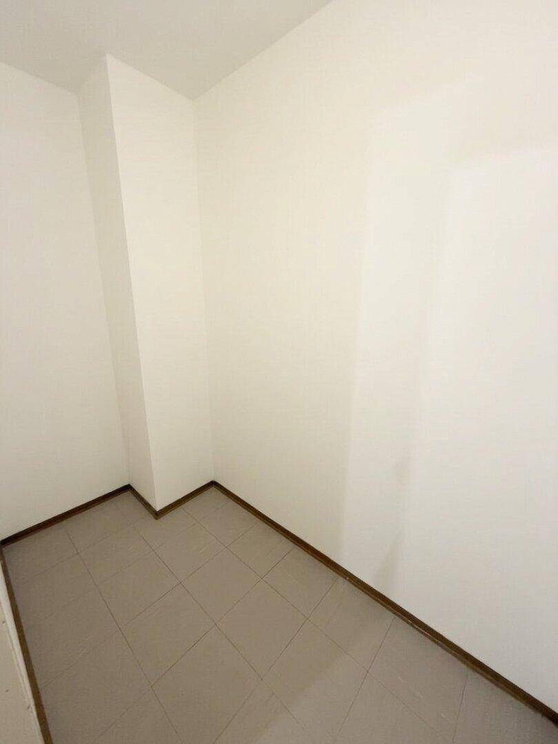 Kleiner Abstellraum mit grauen Fliesen und weißen Wänden.