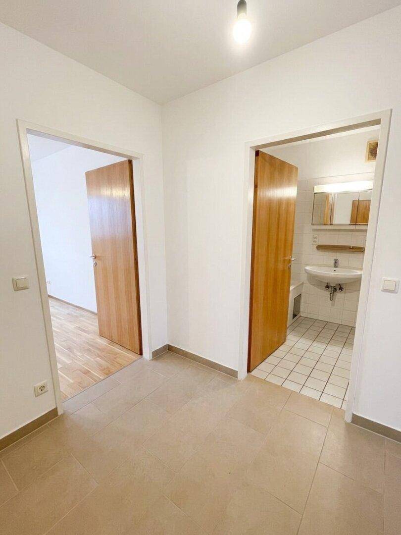 Heller Flur mit beigefarbenen Fliesen und Zugang zu Bad und weiteren Zimmern.