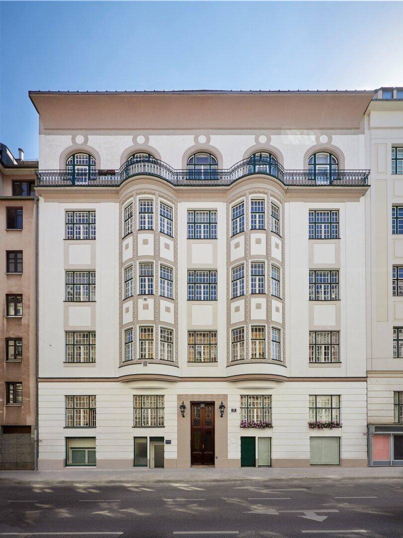 Elegante historische Fassade eines Stadthauses mit Erkern, Balkonen und dekorativen Elementen an einem sonnigen Tag.