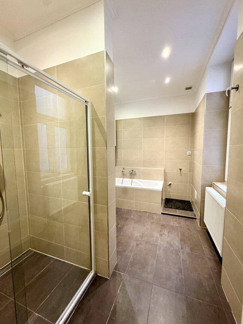 Modernes Badezimmer mit beigefarbenen Fliesen, Dusche und Badewanne.