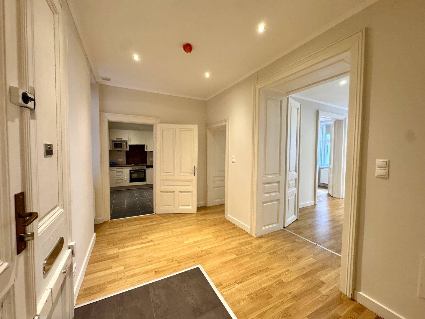Geräumiger Eingangsbereich mit Parkettboden und Blick in die Küche und weitere Zimmer.
