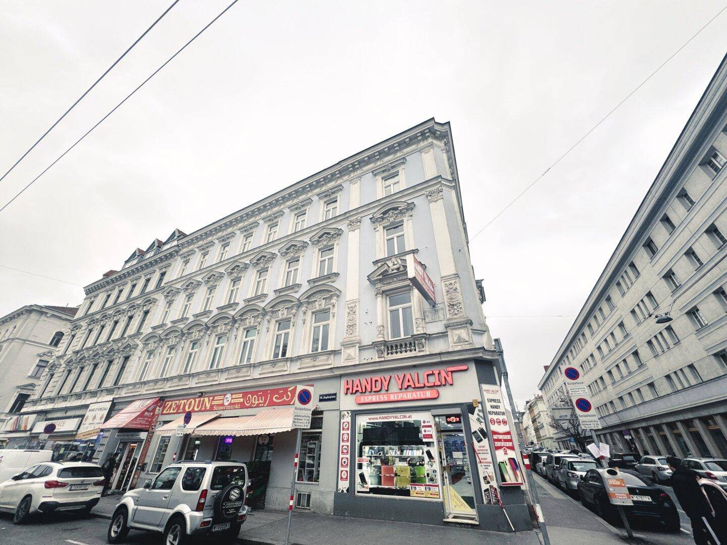 Historisches Eckgebäude in der Stadt mit Geschäften im Erdgeschoss und Wohnungen darüber.