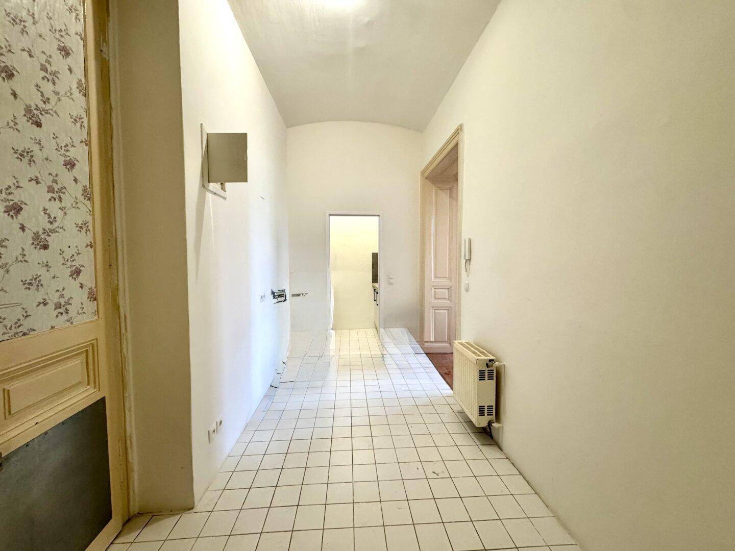 Langer Flur mit Fliesenboden und Zugang zu weiteren Räumen der Wohnung.
