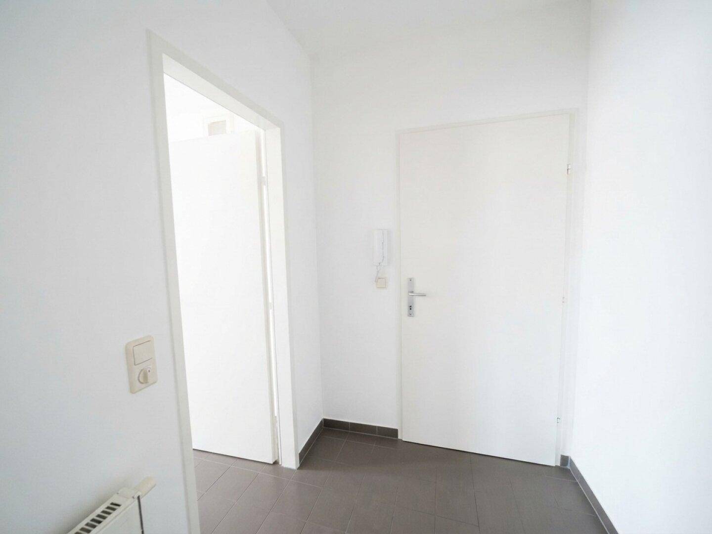 Eingangsbereich mit Fliesenboden und weiß gestrichenen Wänden.