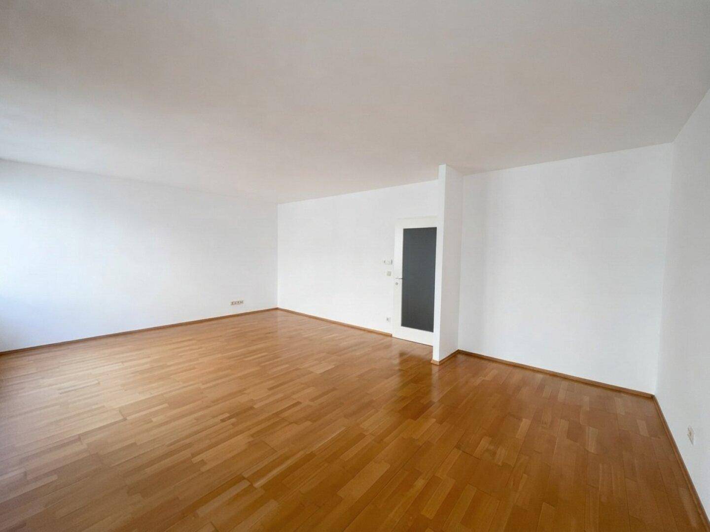 Geräumiger, leerer Raum mit Parkettboden und weiß gestrichenen Wänden, ideal für Möbel.
