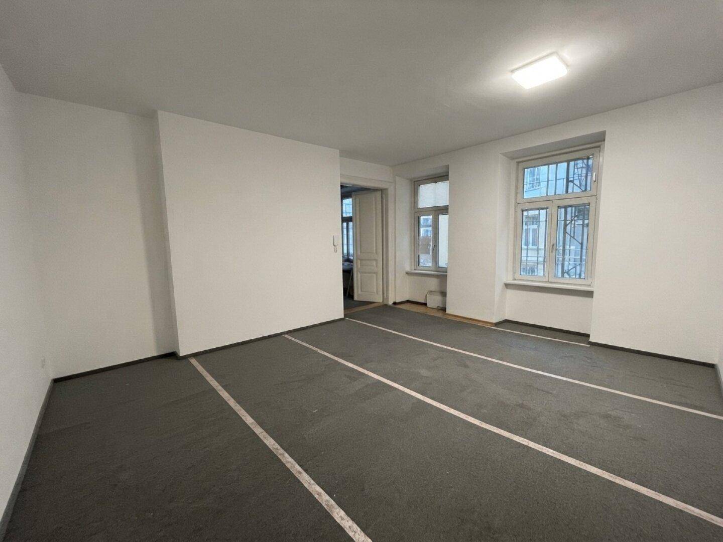 Geräumiges, helles Zimmer mit Teppichboden und zwei Fenstern, die viel Tageslicht hereinlassen.