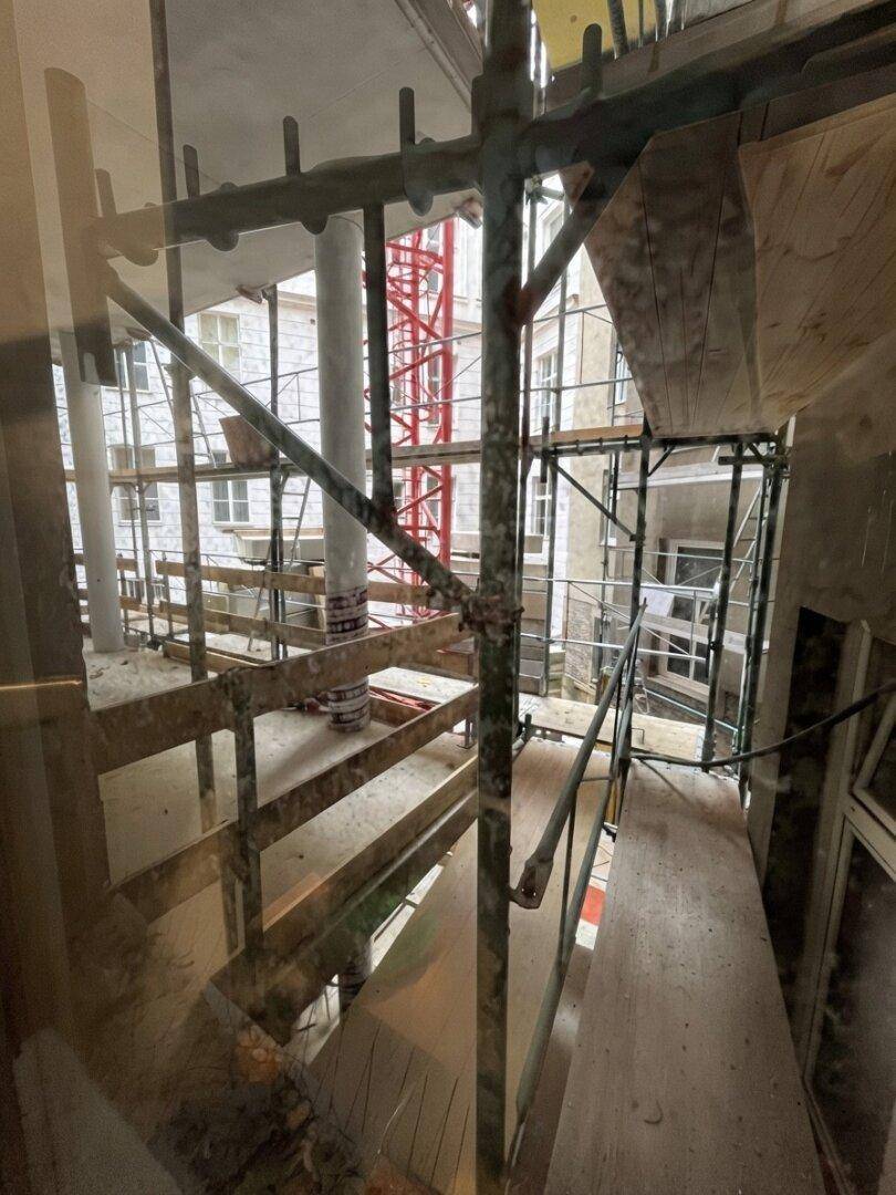 Innenansicht eines Gebäudes im Rohbauzustand mit Gerüst und sichtbaren Bauelementen.