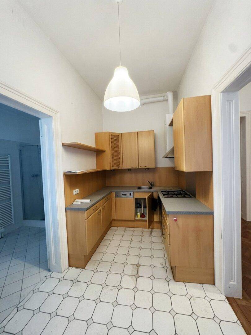 Funktionale Küche mit Holzschränken, Gasherd und gefliestem Boden in gutem Zustand.