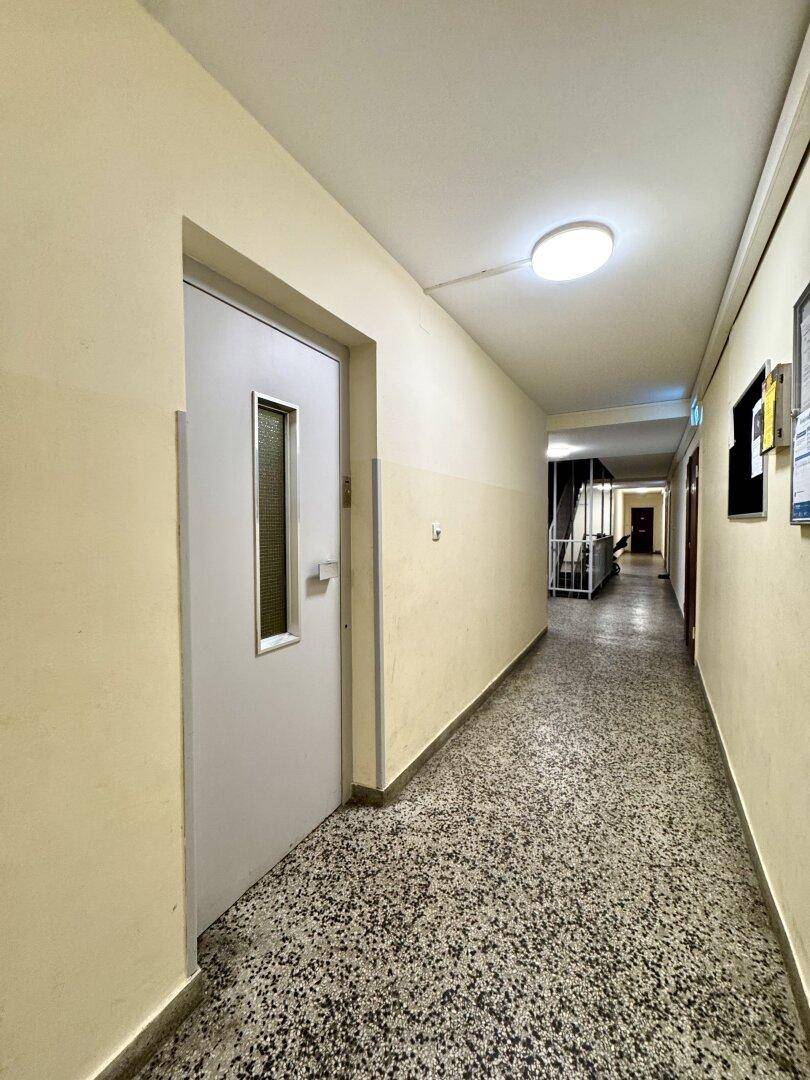 Langer Flur mit Terrazzoboden und Türen zu den einzelnen Wohneinheiten.