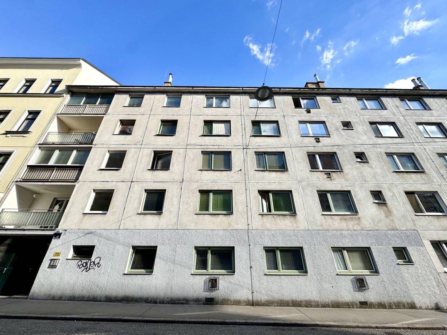 Fassade eines Mehrfamilienhauses mit mehreren Fenstern und Balkonen.