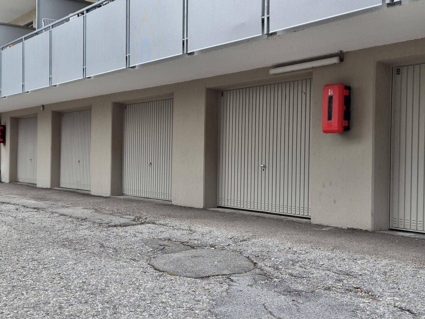 Reihe von geschlossenen Garagentoren an der Fassade eines modernen Wohngebäudes.