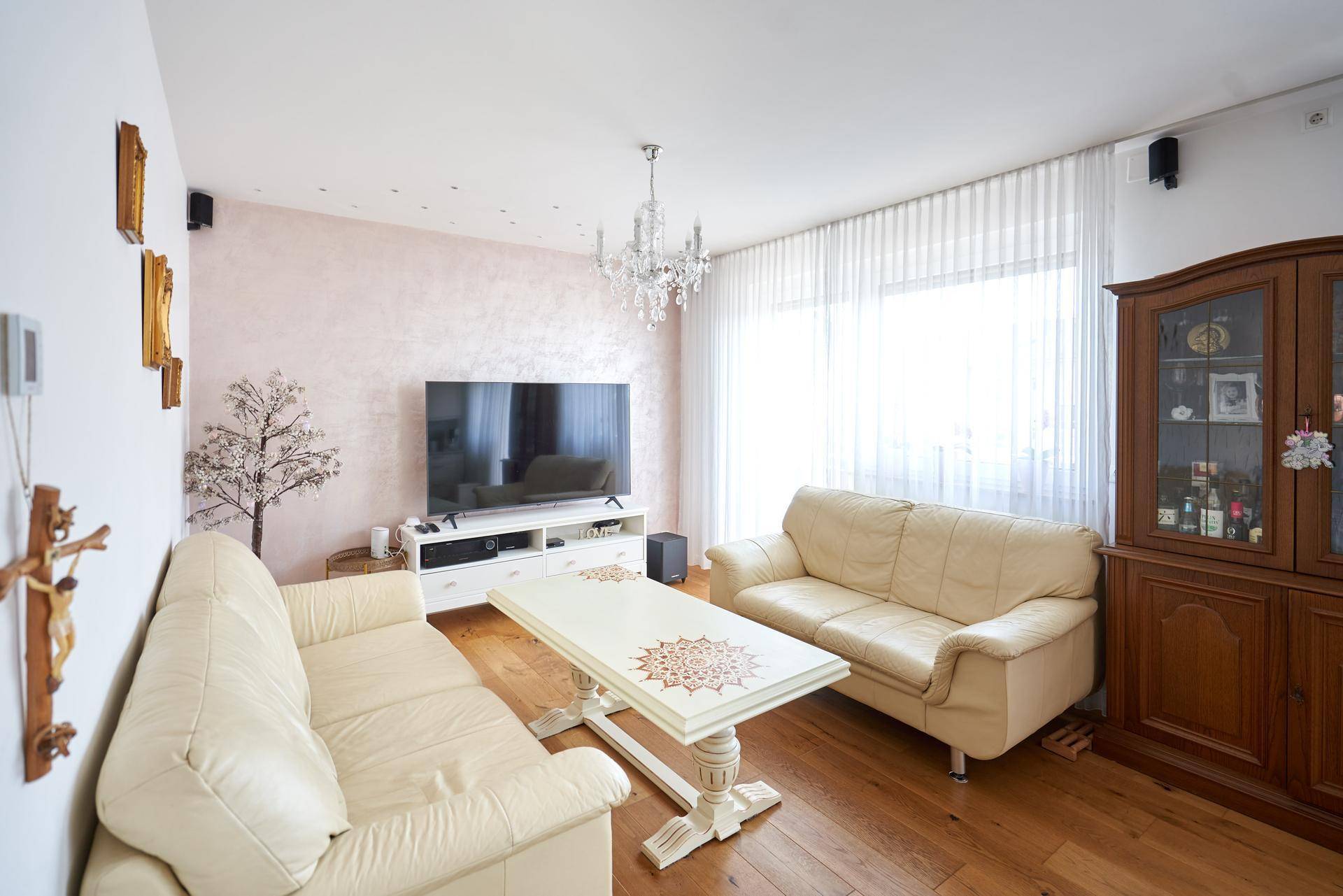 Gemütliches Wohnzimmer mit hellen Sofas, Holzboden und einem großen Fenster für viel Tageslicht.