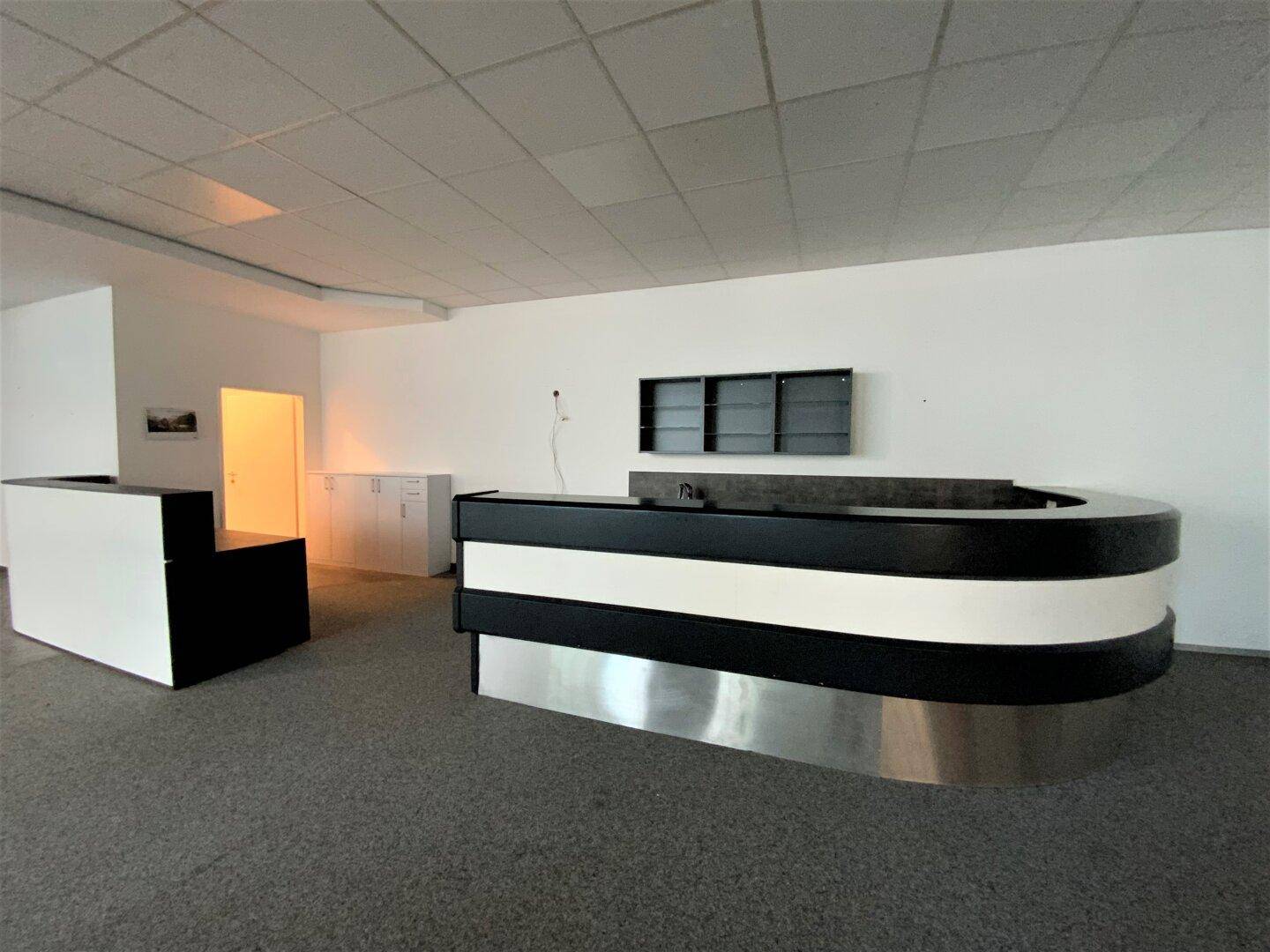 Empfangsbereich mit zwei modernen Theken in Schwarz-Weiß und Teppichboden, ideal für Kundenempfang.