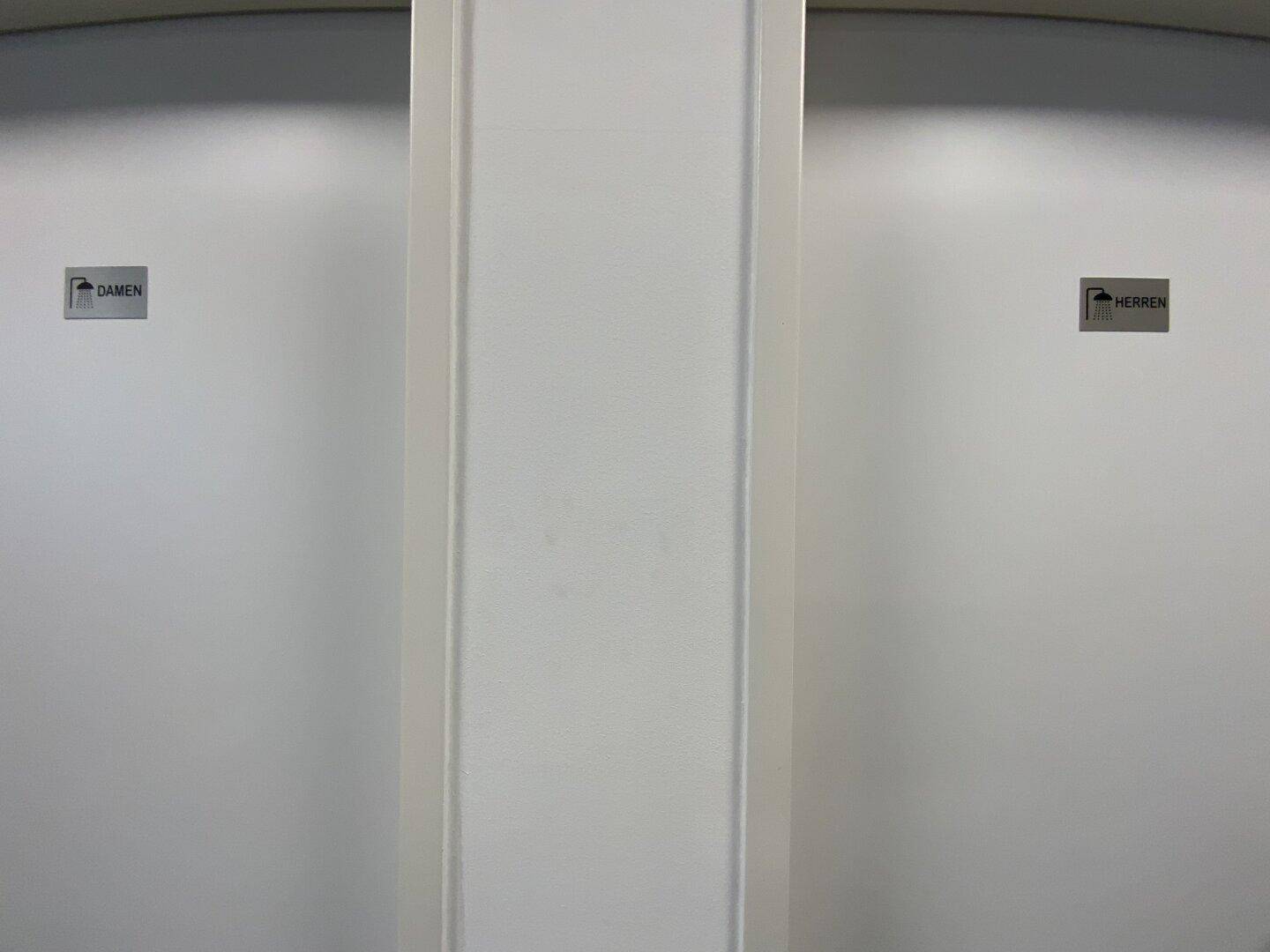 Zwei Toilettentüren mit Beschriftung für Damen und Herren, in einem schlichten, funktionalen Design.
