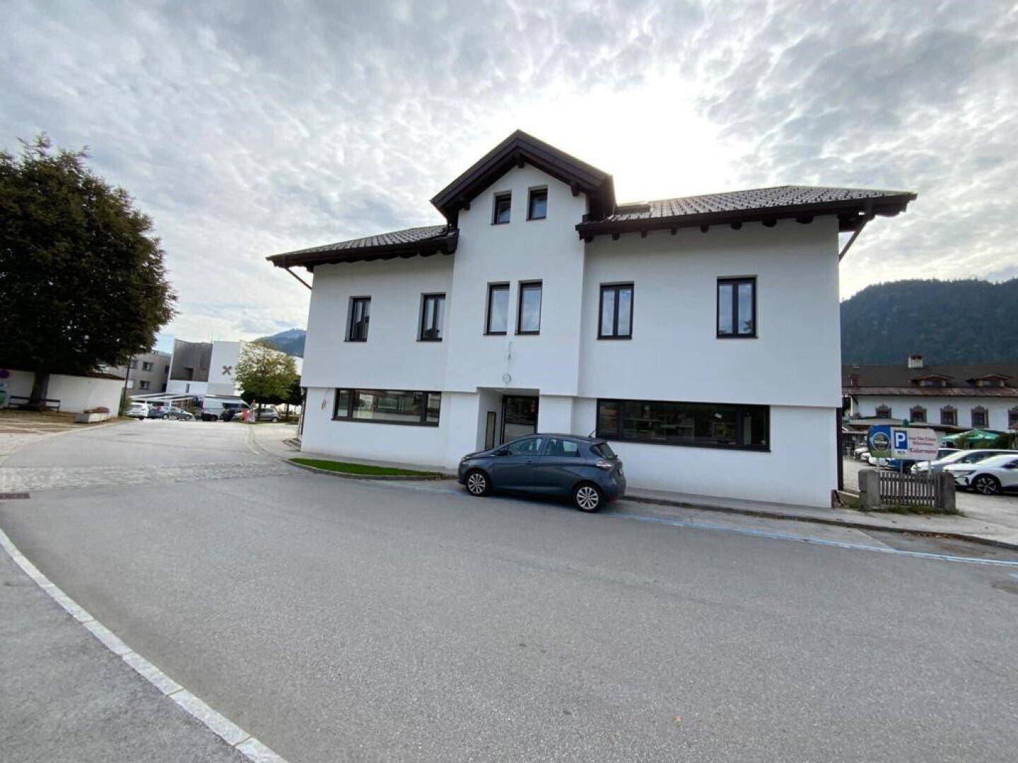 Weißes Mehrfamilienhaus mit traditioneller Architektur an einer Straße gelegen.