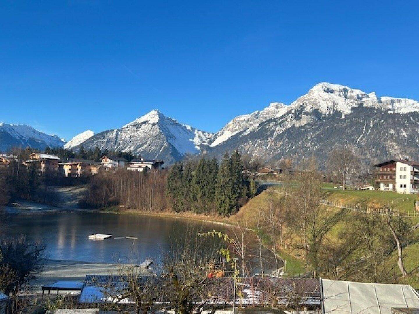 Weitläufiger Blick auf einen zugefrorenen See und die majestätischen schneebedeckten Berge im Winter.
