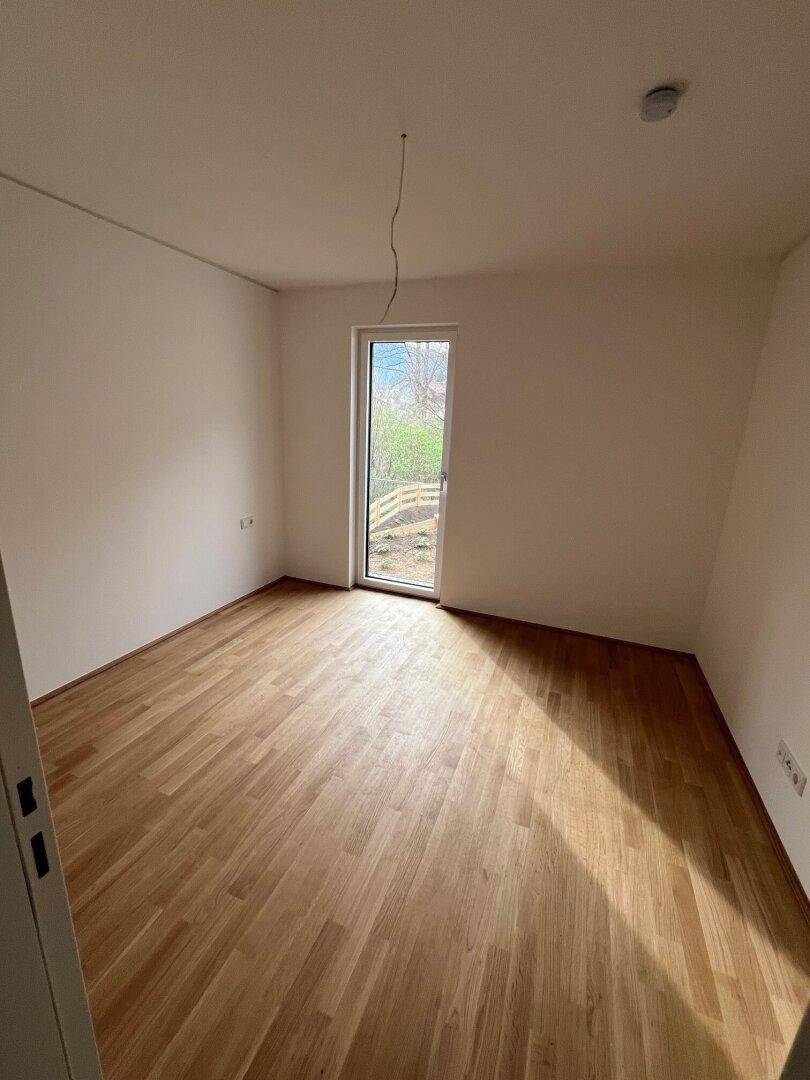 Helles Schlafzimmer mit Holzboden und Zugang zu einem Außenbereich, ideal für Ruhe und Entspannung.
