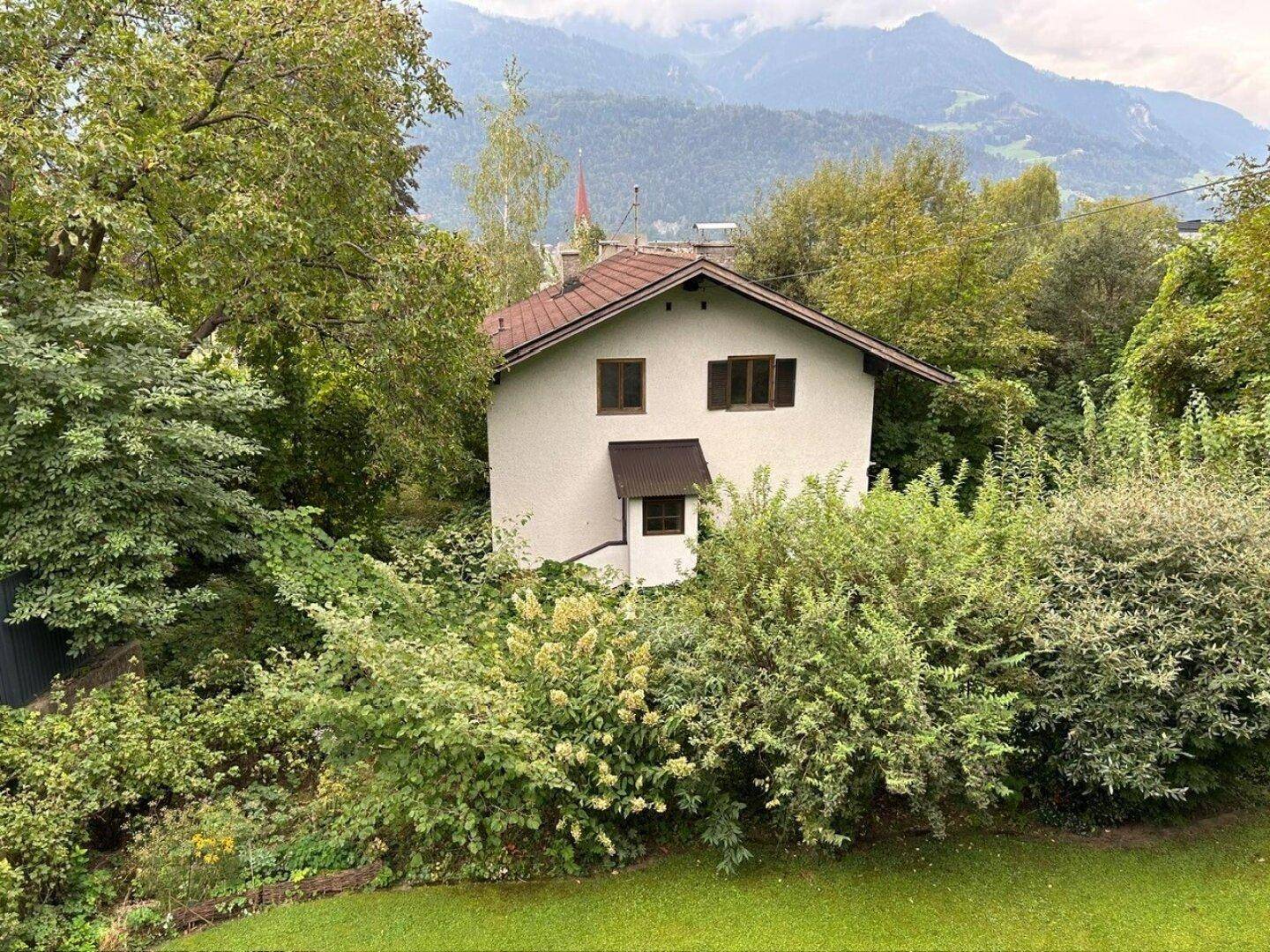 Idyllisches Haus inmitten grüner Natur mit weitem Blick auf die umliegende Berglandschaft.