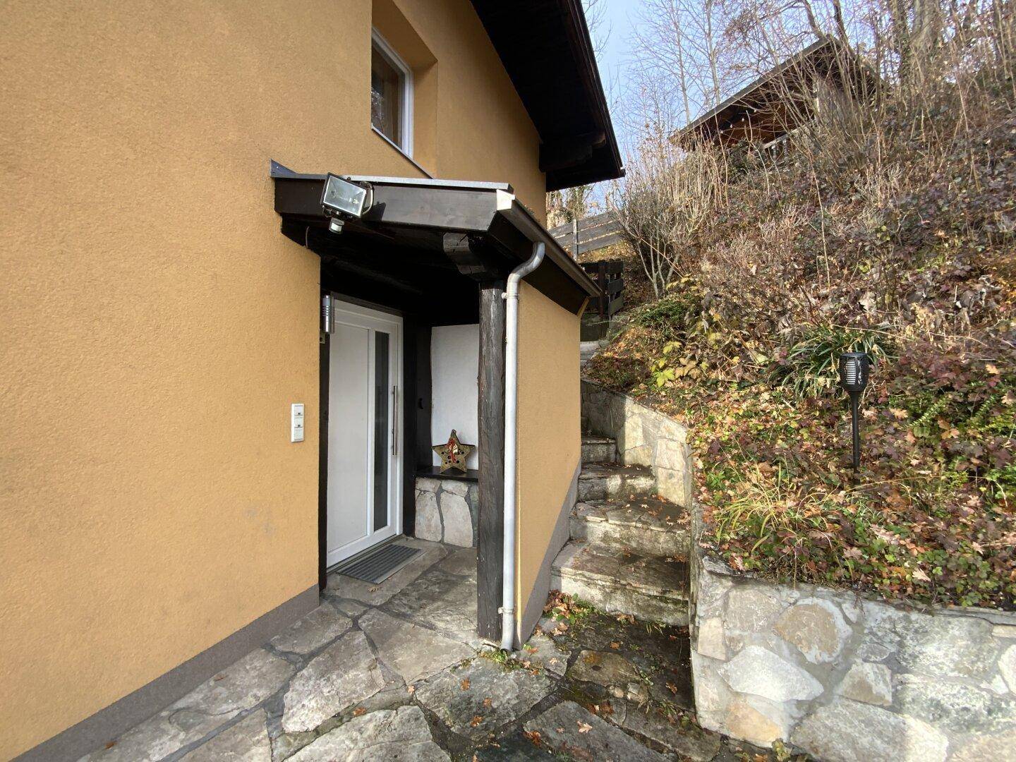 Eingangsbereich des Hauses mit Steinplatten und Treppe zur oberen Ebene.