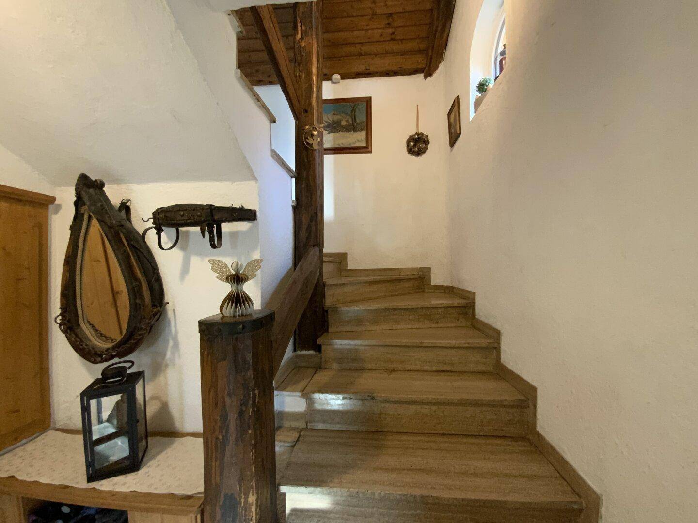 Holztreppe im Flur mit traditionellen Dekorationselementen und sichtbaren Balken.