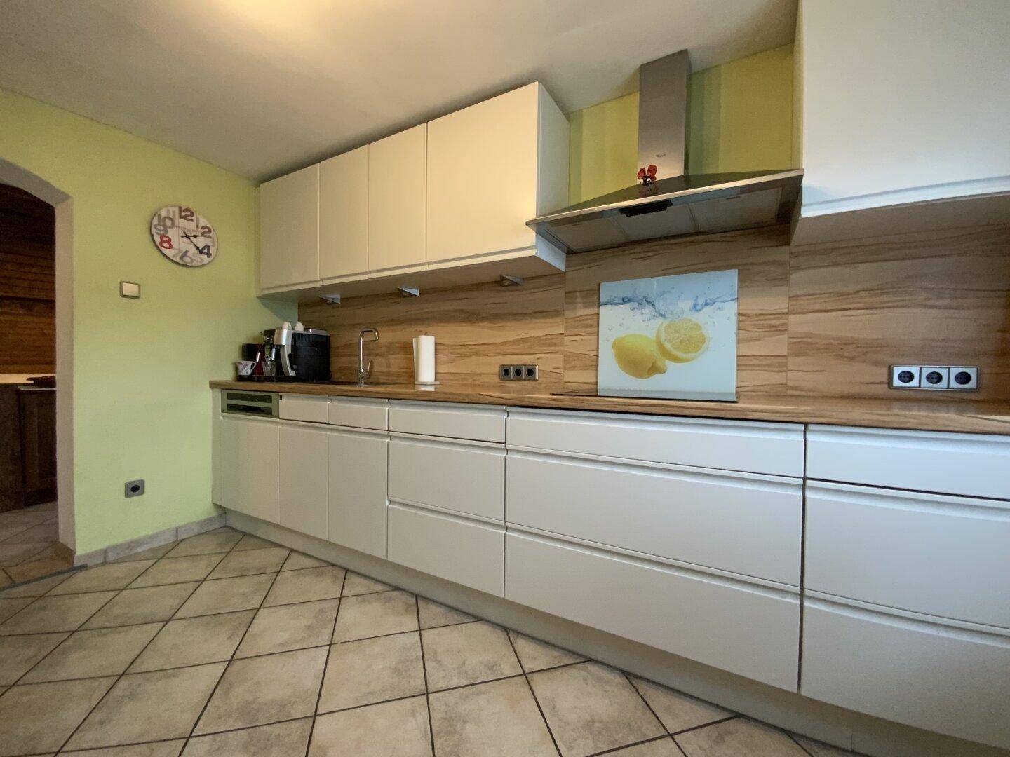 Küchenzeile mit Spüle, Kochfeld und Dunstabzugshaube in modernem Design.